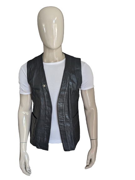 Leather waistcoat without closure. Black colored with silver colored star. Size M / L.