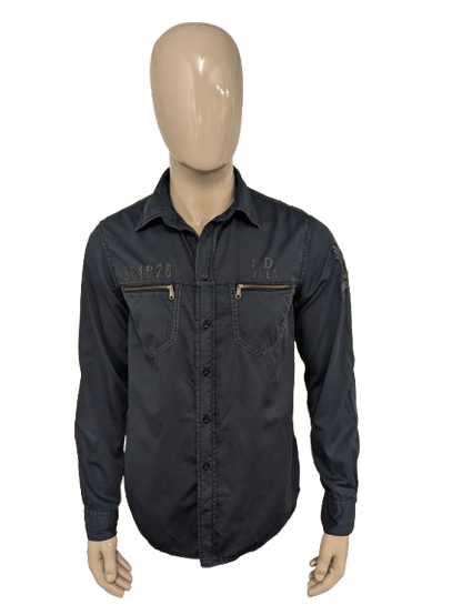 Devinez la chemise en jeans. Bleu foncé coloré avec des accents à fermeture éclair avec des sacs à poitrine. Taille L.