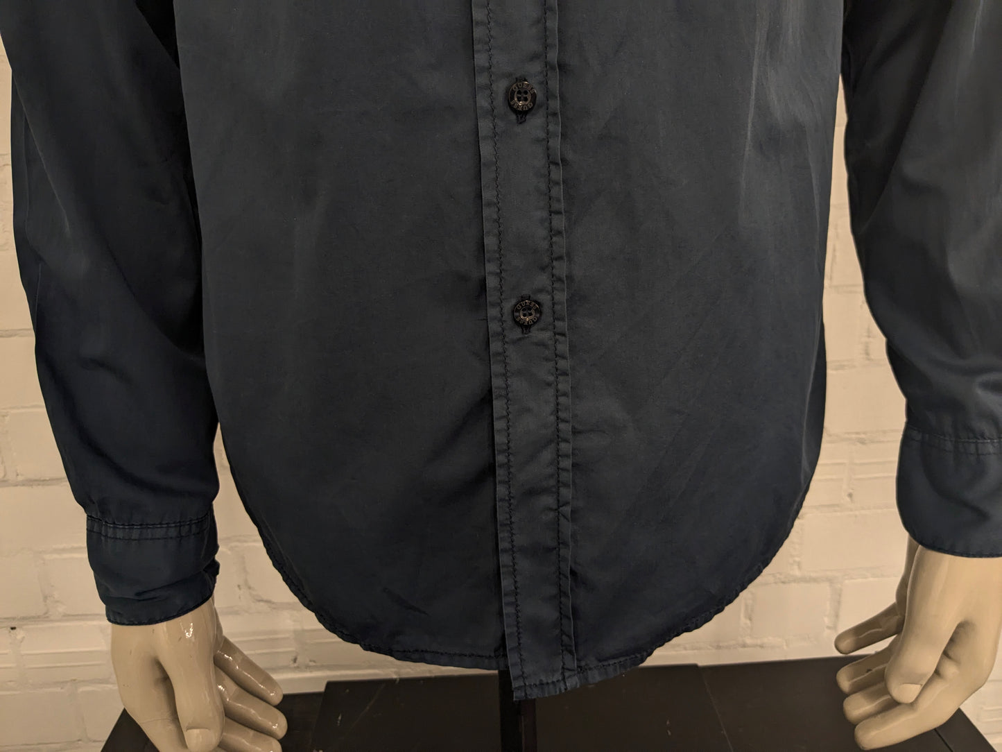Devinez la chemise en jeans. Bleu foncé coloré avec des accents à fermeture éclair avec des sacs à poitrine. Taille L.