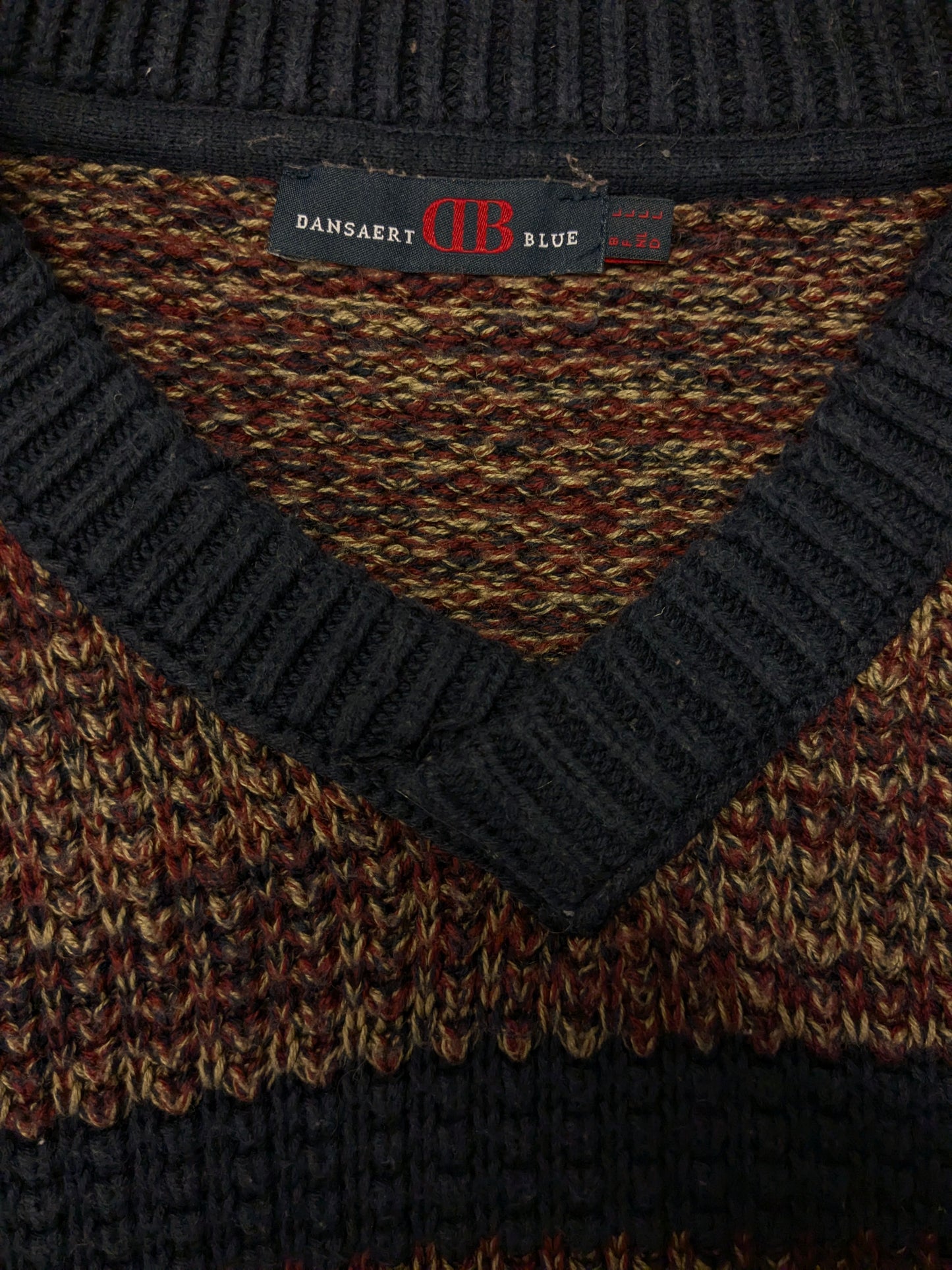 Pull en laine bleu Dansaert avec col en V. Kaki bleu rouge mélangé. Taille L. 10% de laine.