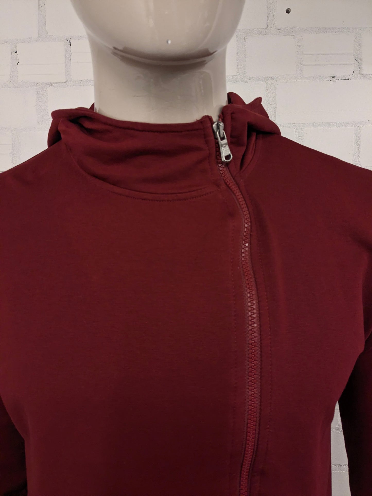 Pure White vest met capuchon en asymmetrische rits. Donker Rood gekleurd. Maat L.