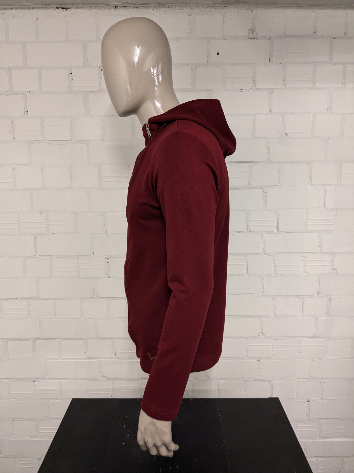 Pure White vest met capuchon en asymmetrische rits. Donker Rood gekleurd. Maat L.