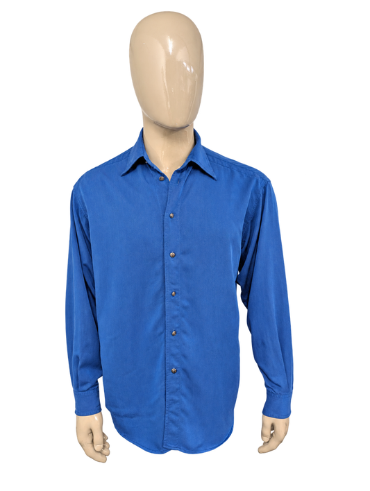 Vintage Versace Jeans Couture overhemd. Blauw gemêleerd met licht glanzend effect en de mooie iconische knopen. Maat L. – voorzijde, vrijstaand.