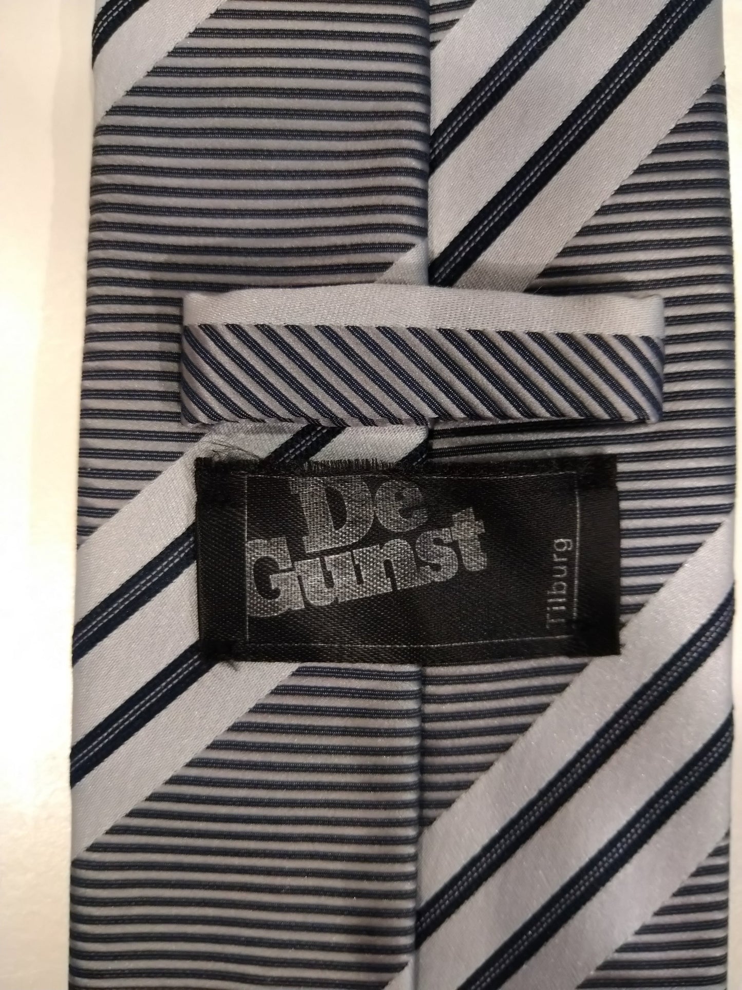 De Gunst Tilburg vintage polyester stropdas. Zwart / Zilver gestreept