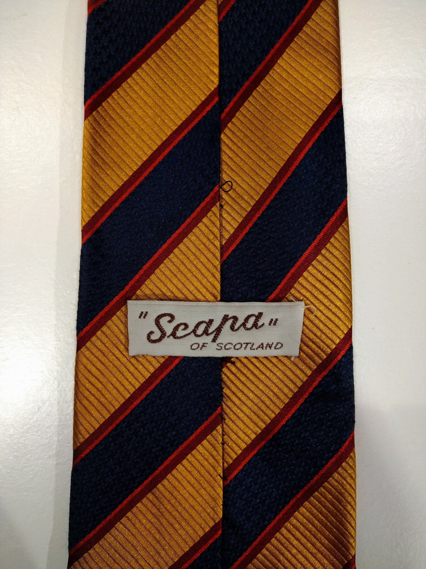 Cravatta di seta scapa o scozzese. Strisce rosse blu oro.