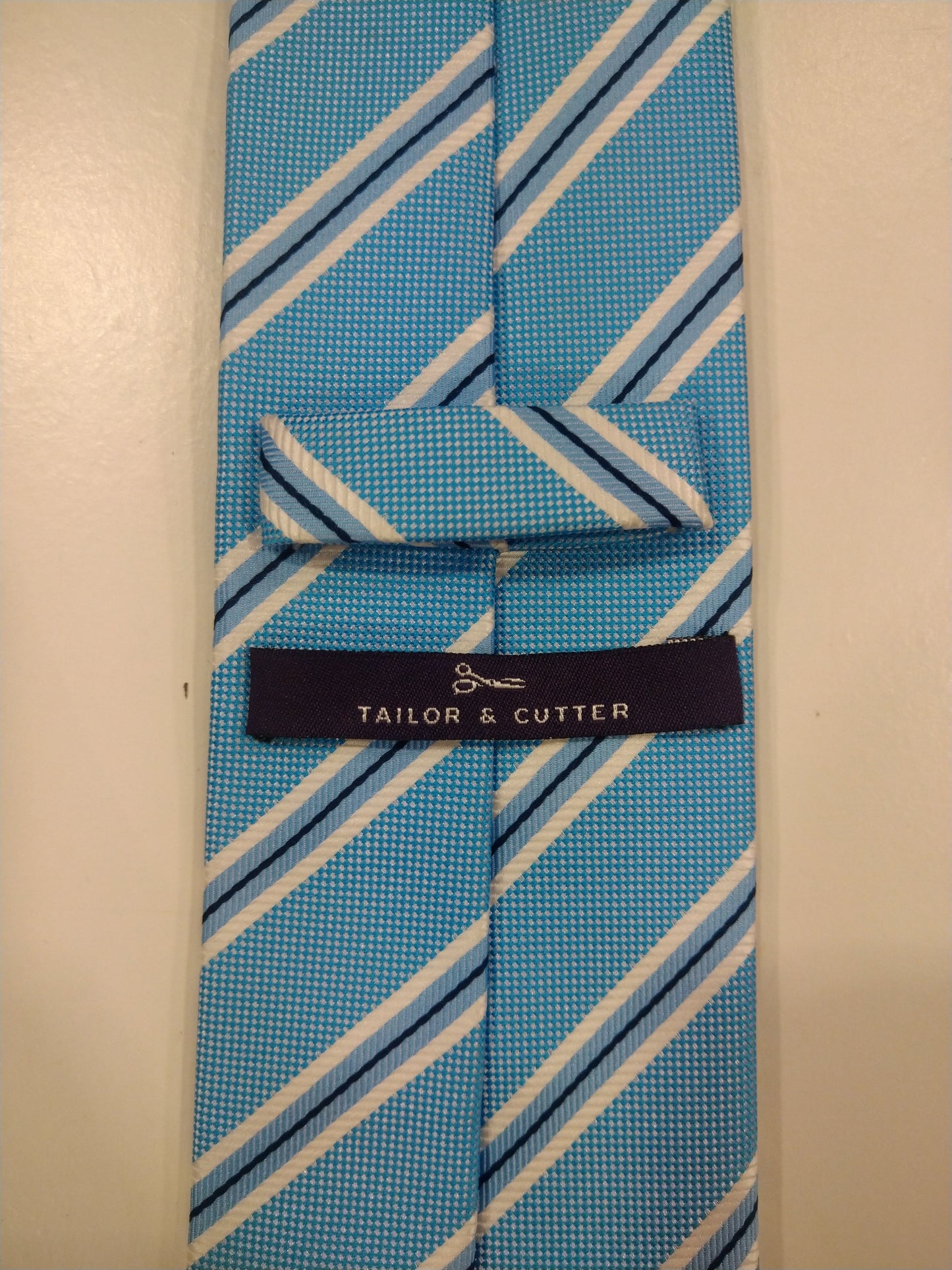 Cravatta in poliestere su misura e taglierina. Strisce bianche blu.